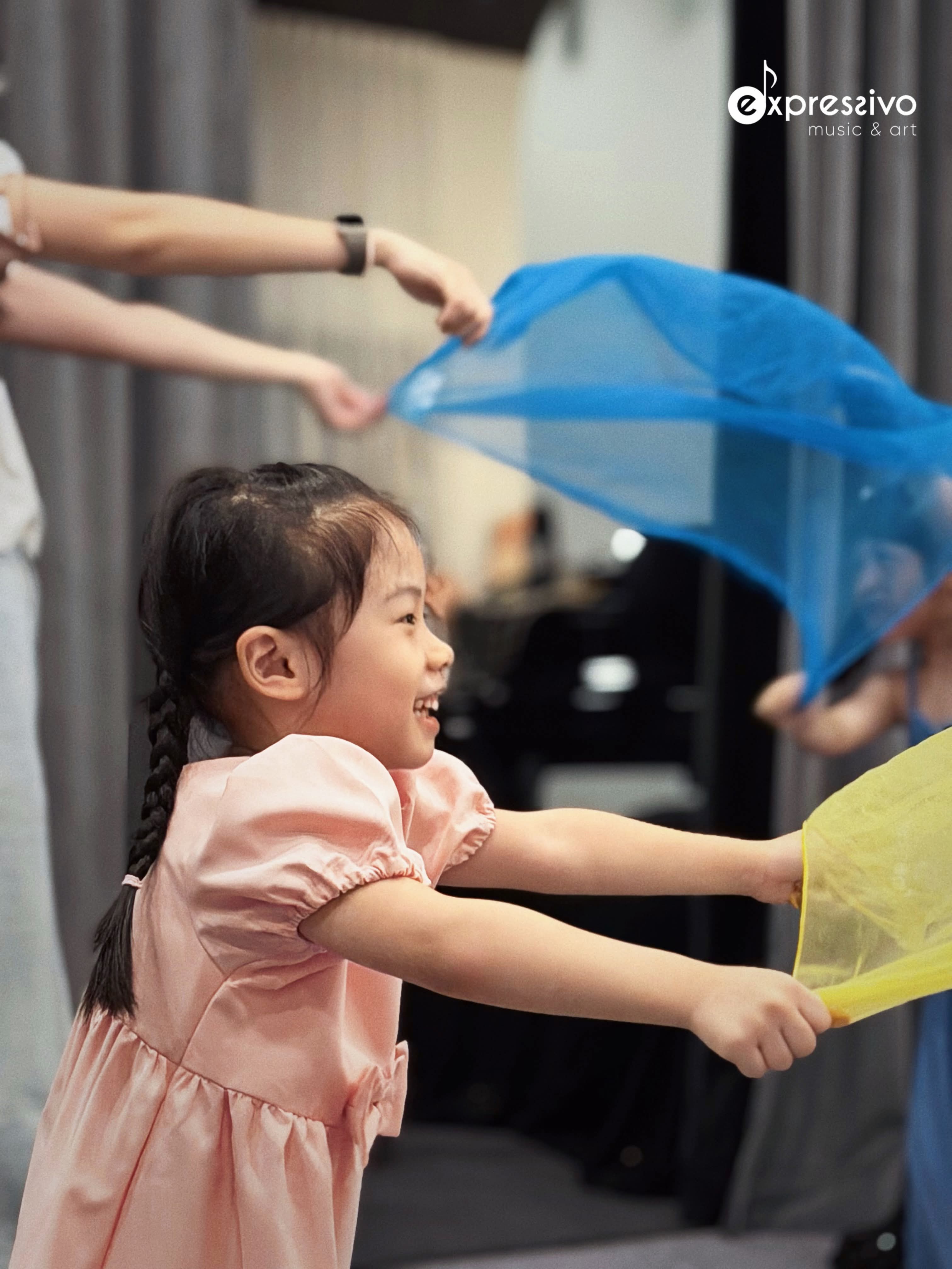 Young performer moving with a blue scarf on stage