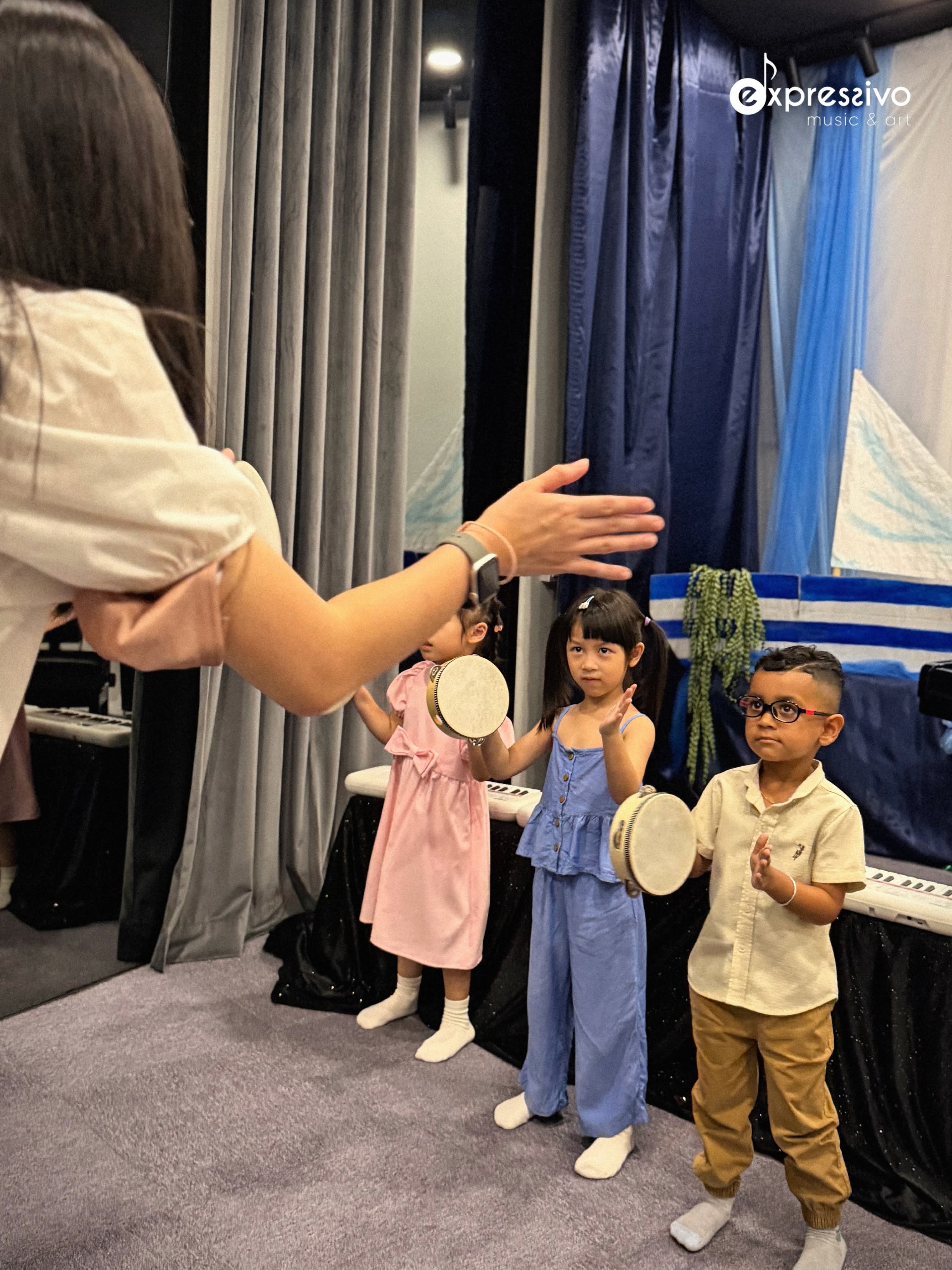 Teacher guiding young performers with percussion instruments