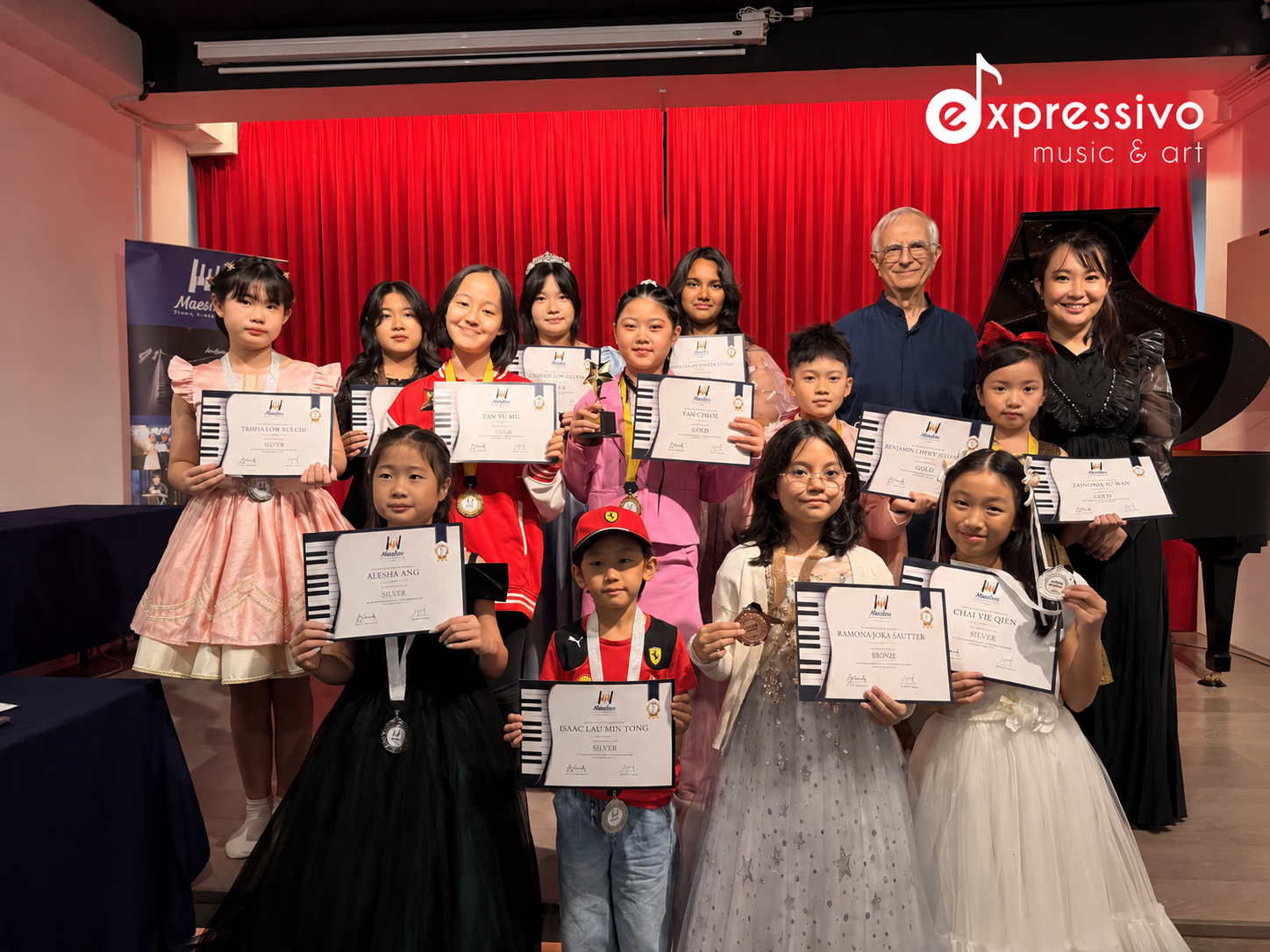 Maestoso competition awardees holding certificates with teachers and a grand piano