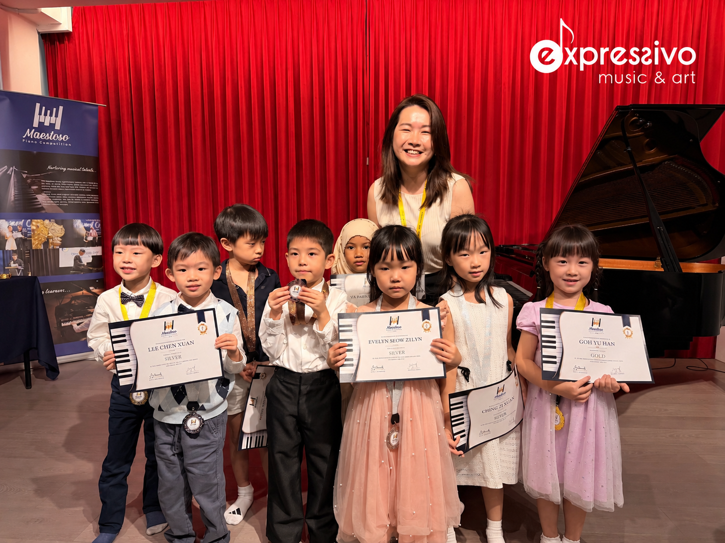 Young Maestoso competitors holding certificates and medals with their teacher