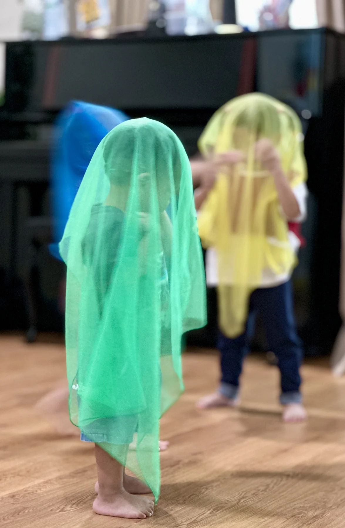 Two young children exploring movement with colourful scarves during an early childhood music activity