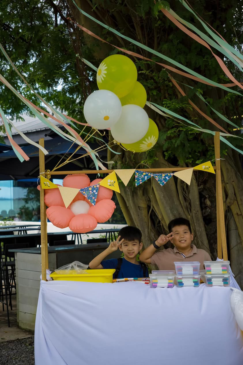 Children at the flower art market booth with balloons and bunting